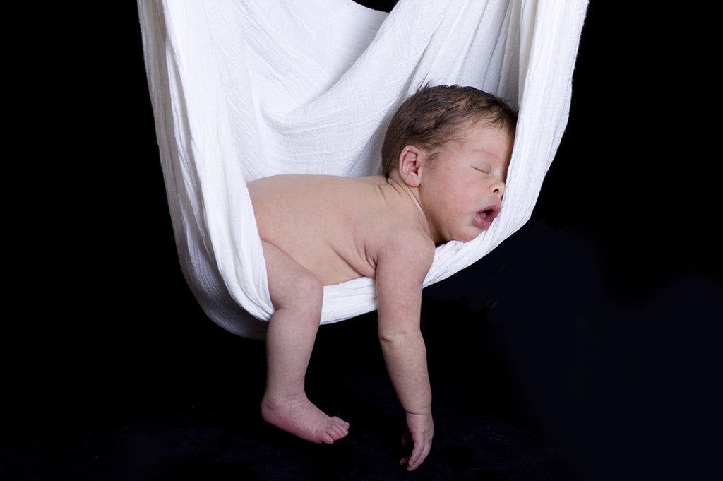 Naked baby asleep in a white hanging blanket