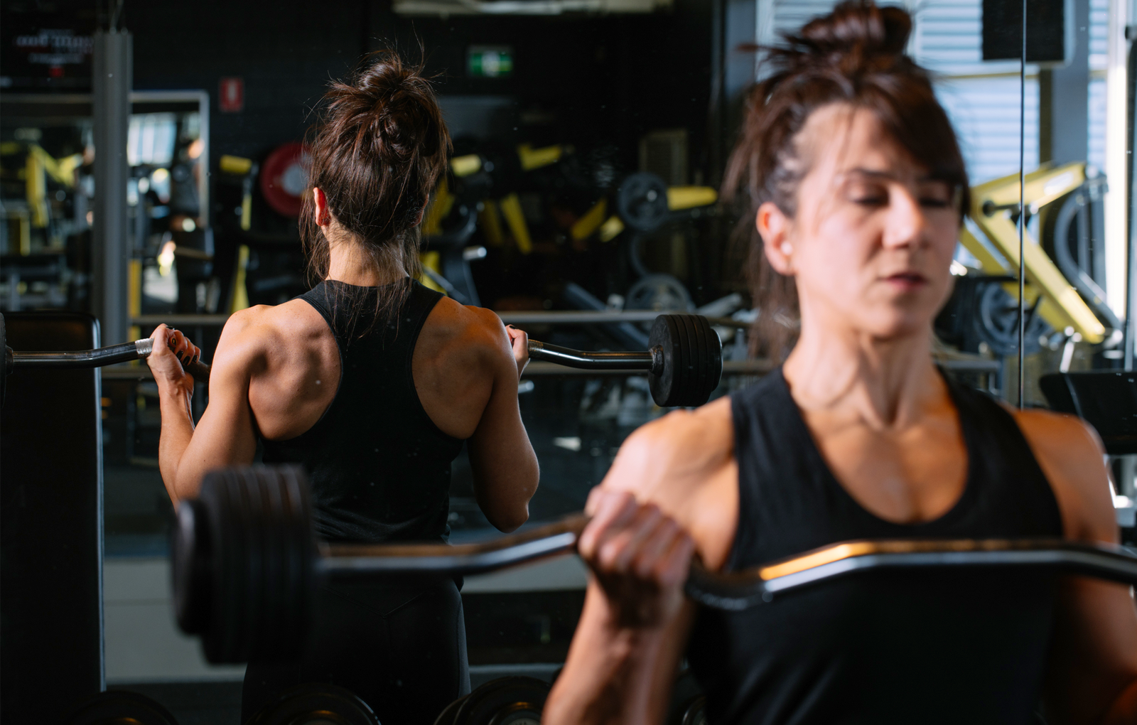Female bodybuilder doing bicep curls wearing a black ECOLITE® Yoga racerback from Kusaga Athletic