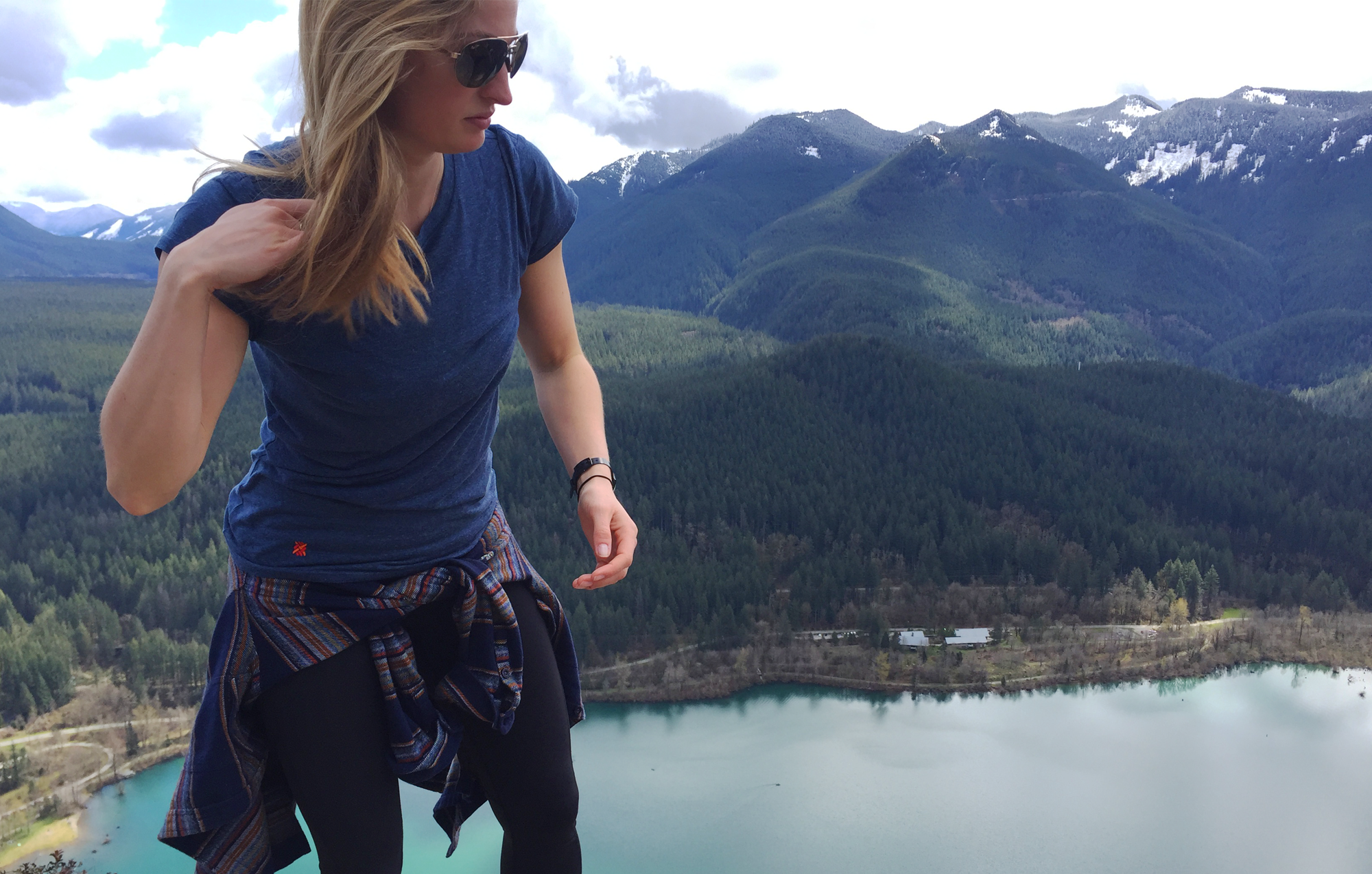 Blond woman standing on a mountain wearing The Greenest Tee on the Planet by Kusaga Athletic